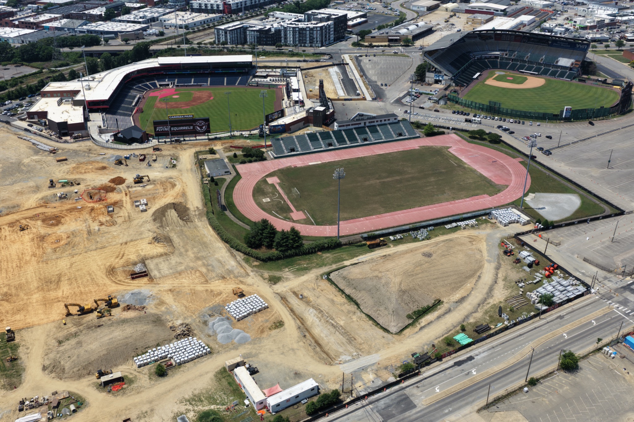 Aerial view of active construction surrounding multiple athletic facilities