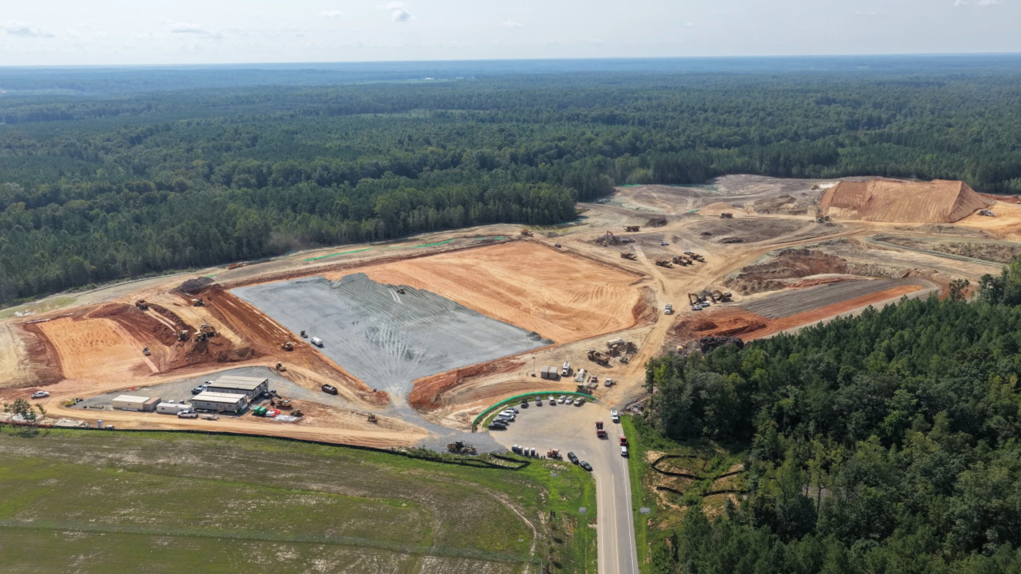 Broader context relating the development area to the access road and surrounding wooded environment.
