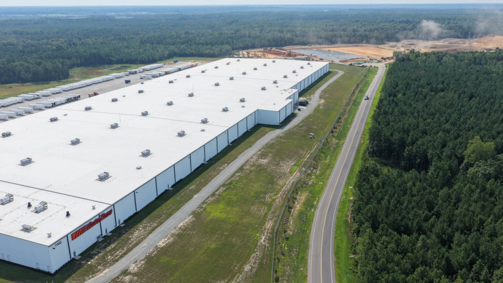 Established logistics facility and new development in one frame, preserving the spatial relationship across the corridor.