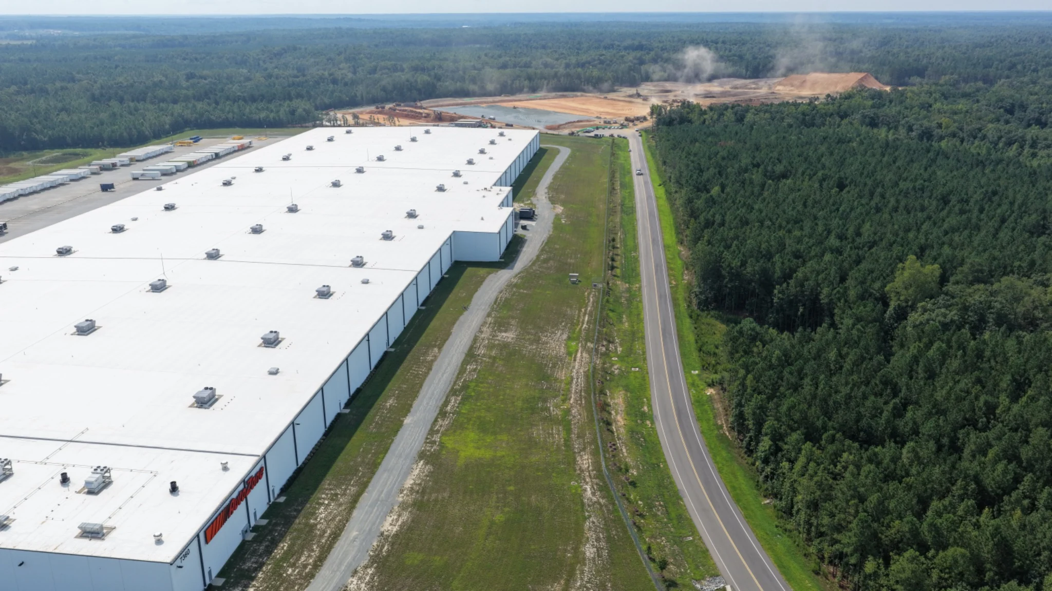 View from the AutoZone side showing the established facility, roadway and active development in the distance.