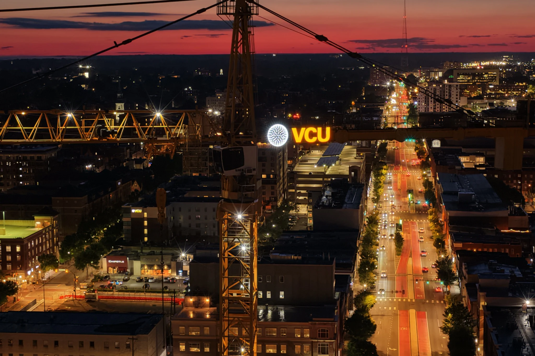 Evening urban view with illuminated VCU branding and visible construction-crane context.