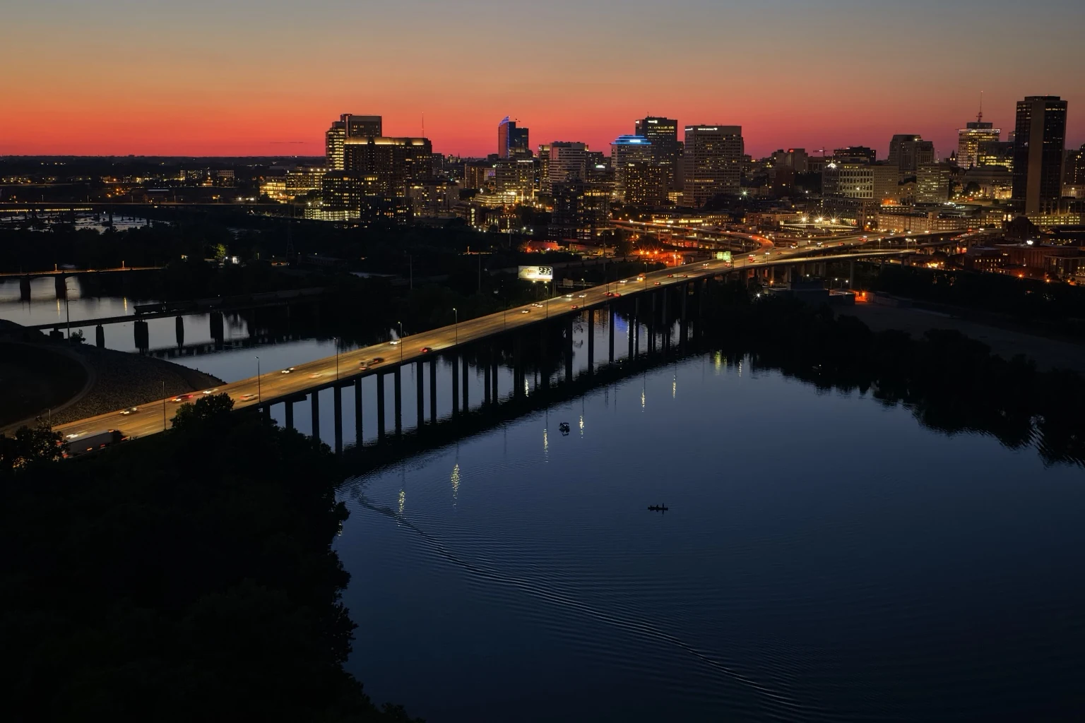 Wide Richmond skyline at dusk with river, bridge and city lights.
