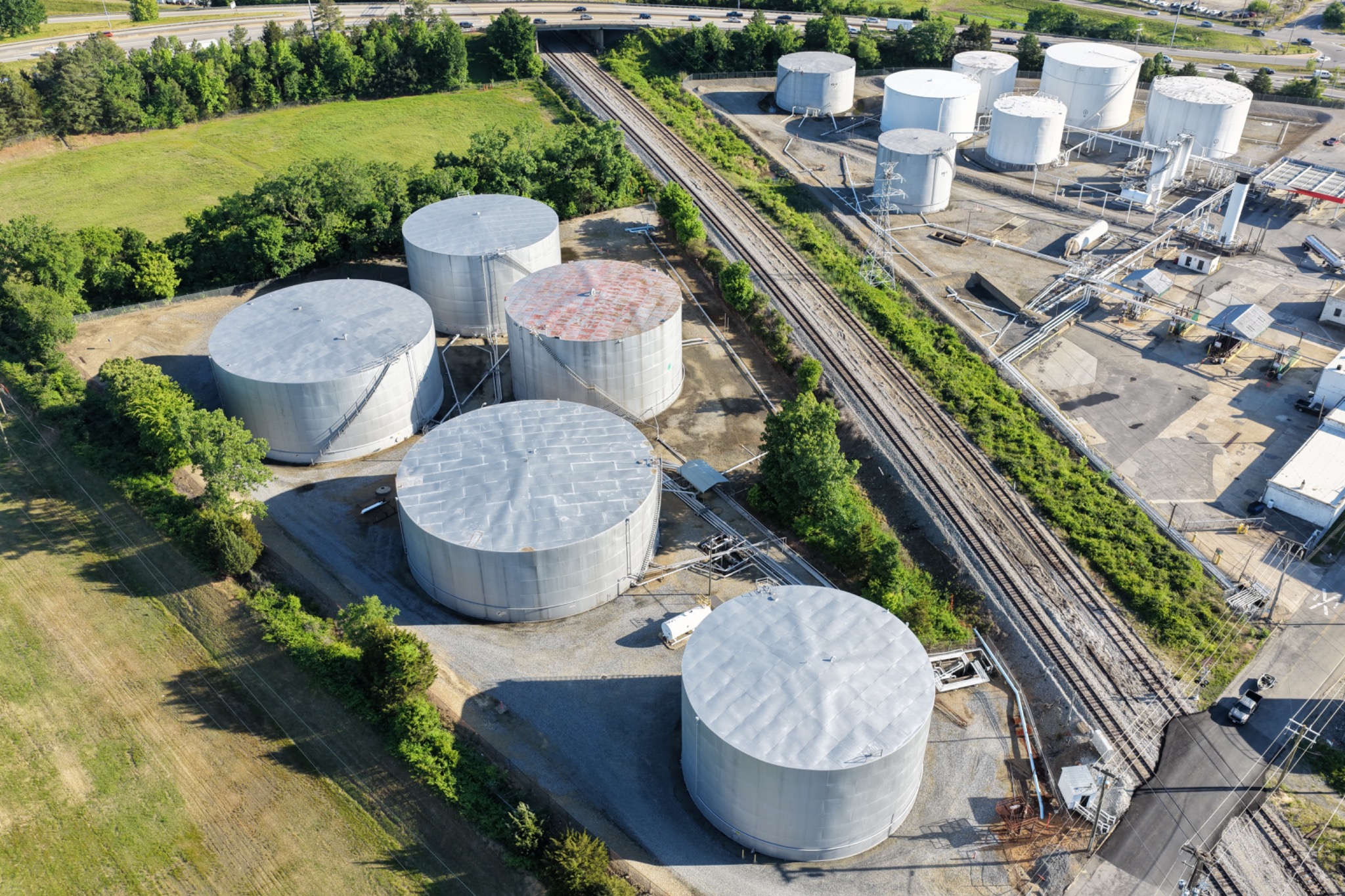 Aerial view of industrial storage tanks, rail access and surrounding site conditions