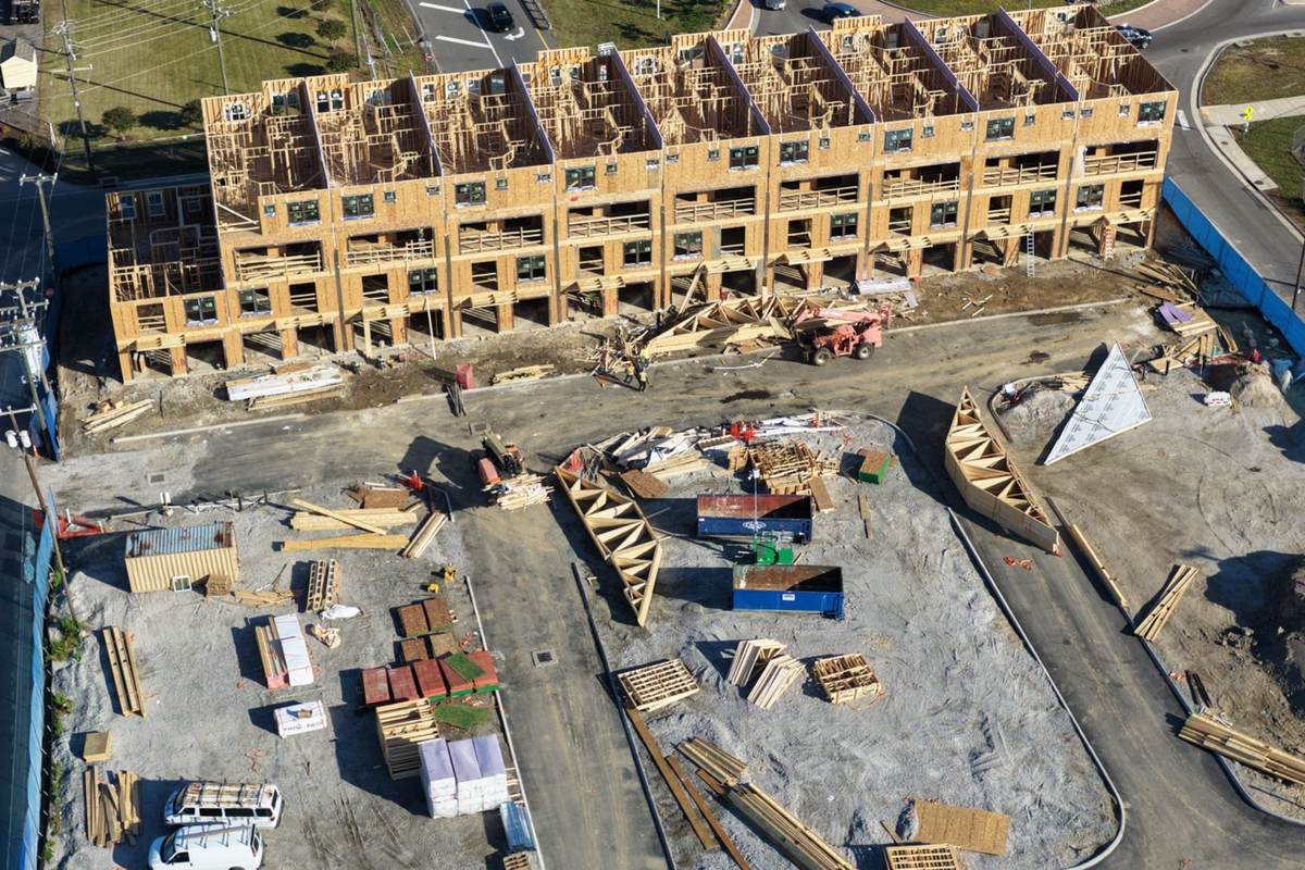 Drone photo showing apartment framing progress, lumber staging, site access, and construction logistics