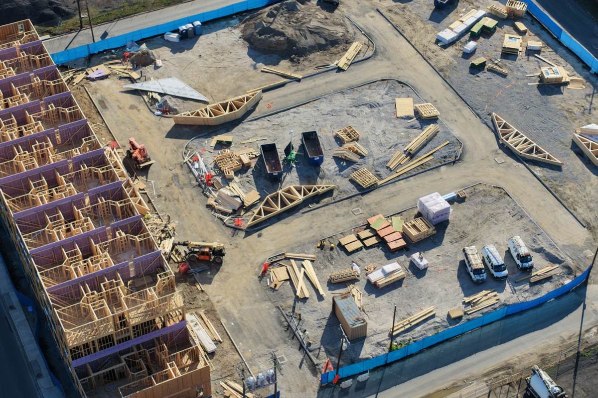 Aerial apartment foundation construction progress with grading, materials, and early site work